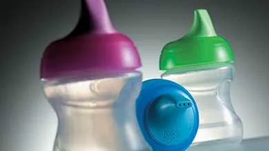 Close-up of three plastic sippy cups with lids in purple, green, and blue.