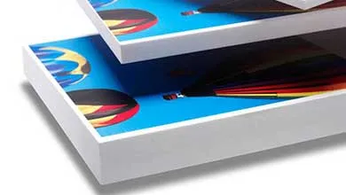 Close-up of two stacked foam boards with thick white edges, printed with colorful hot air balloons on a blue sky background.