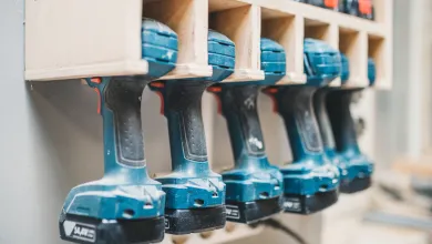 Multiple cordless drills stored vertically on a wall‑mounted rack.