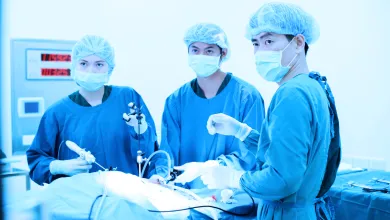 Medical team performing a surgical procedure in an operating room, using sterile instruments and equipment under bright clinical lighting.