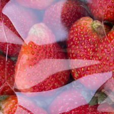 Close-up of bright red strawberries inside a clear plastic clamshell container.